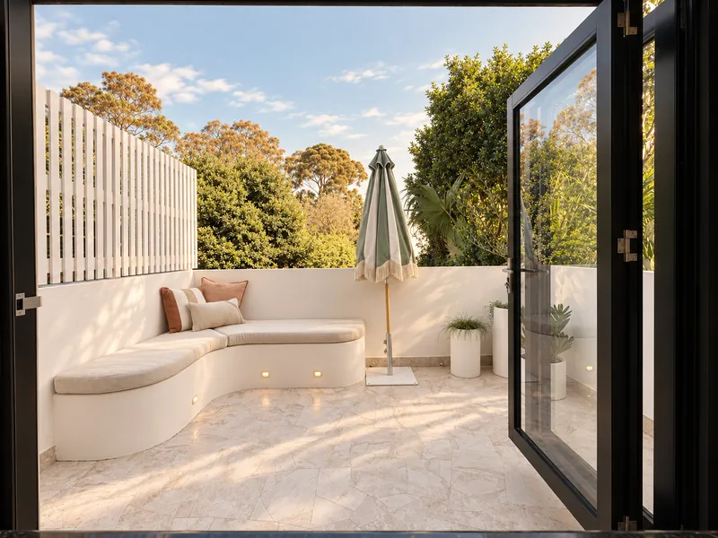Sunny courtyard with curved seating beside a glazed garage conversion