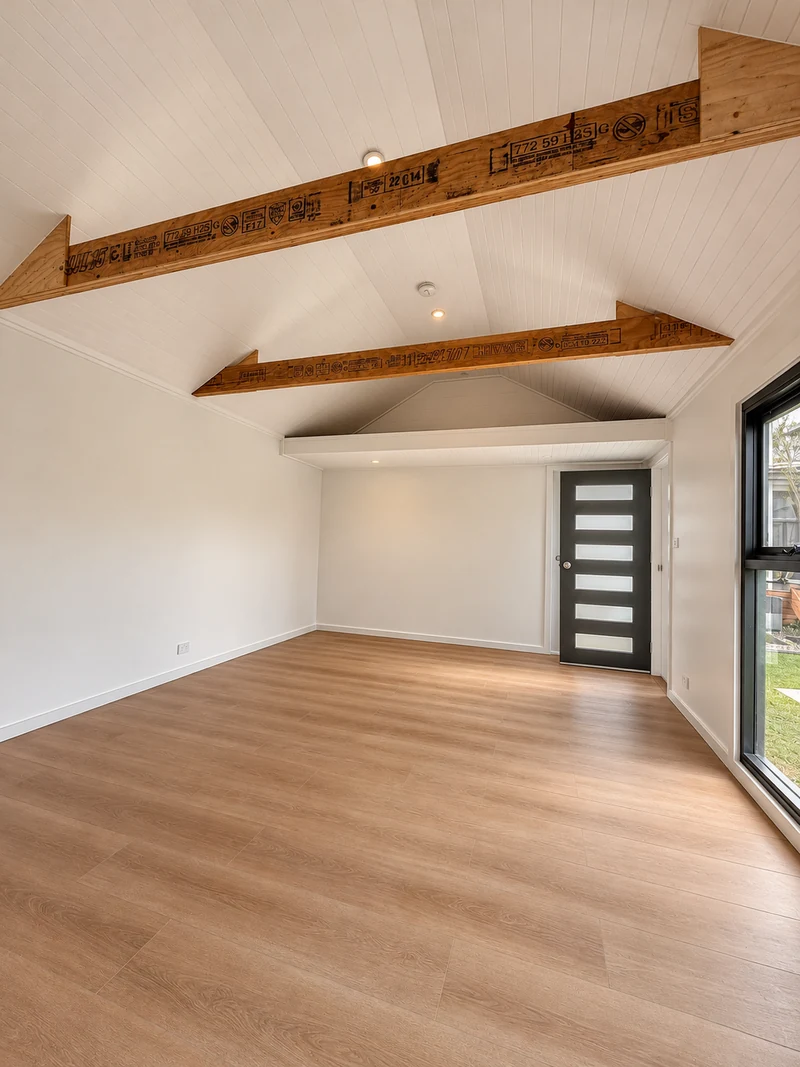 Converted room with timber flooring, exposed roof beams and a glazed entrance door